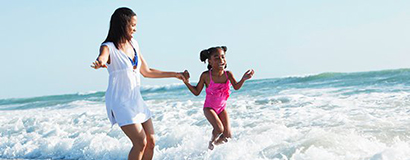 mom and daughter jumping on beach