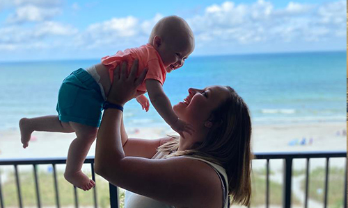 Baby and mother on a balcony overlooking the beach