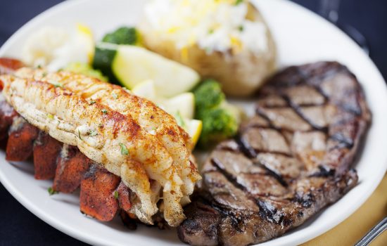 Steak on a plate with lobster, mashed potatoes, and vegetables for dinner