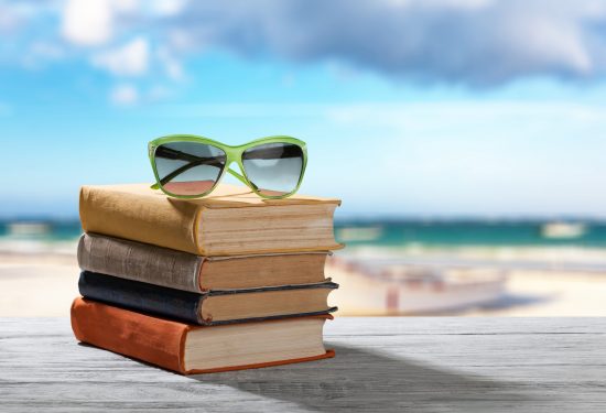 Books and sunglasses on beach background
