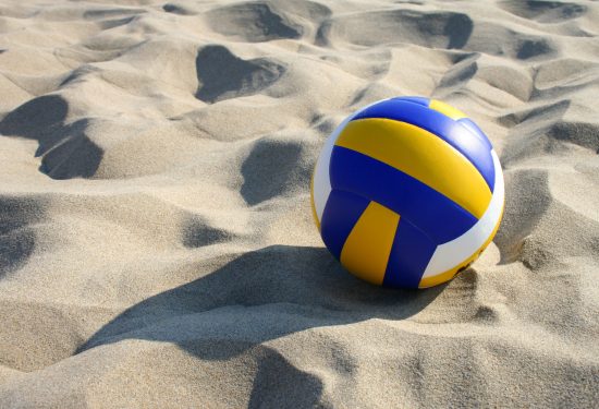 Beach volleyball lying in sand.